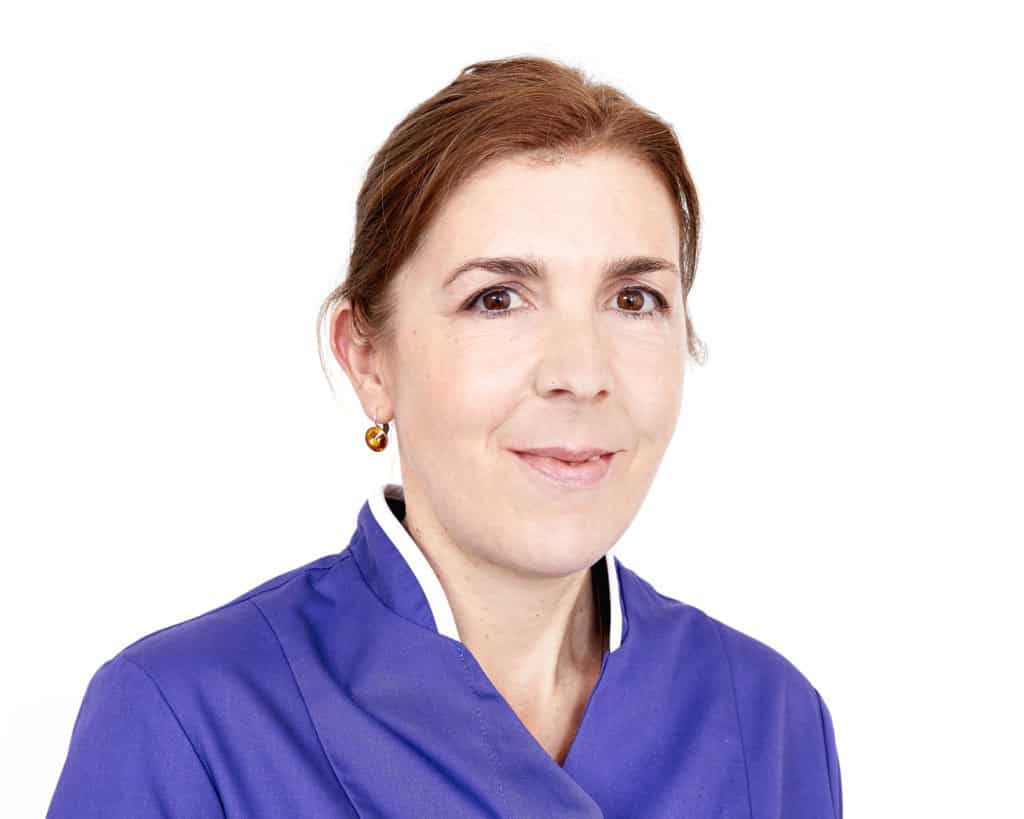 Female healthcare professional in blue uniform smiling.
